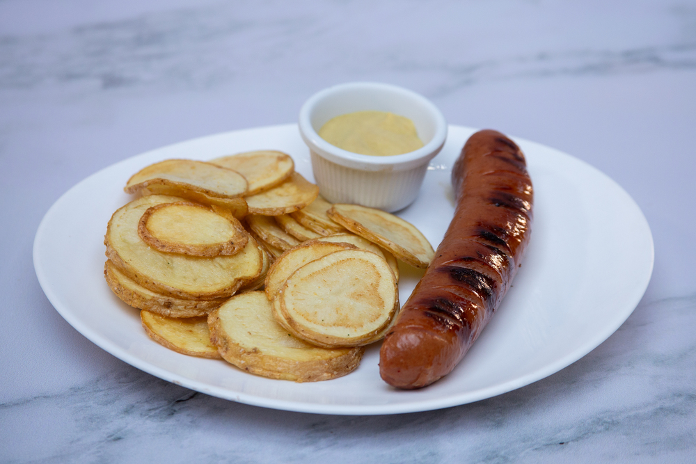 Salchichas de cerdo con acompañamiento de rodajas de papa, servidas y preparadas en Heidi's